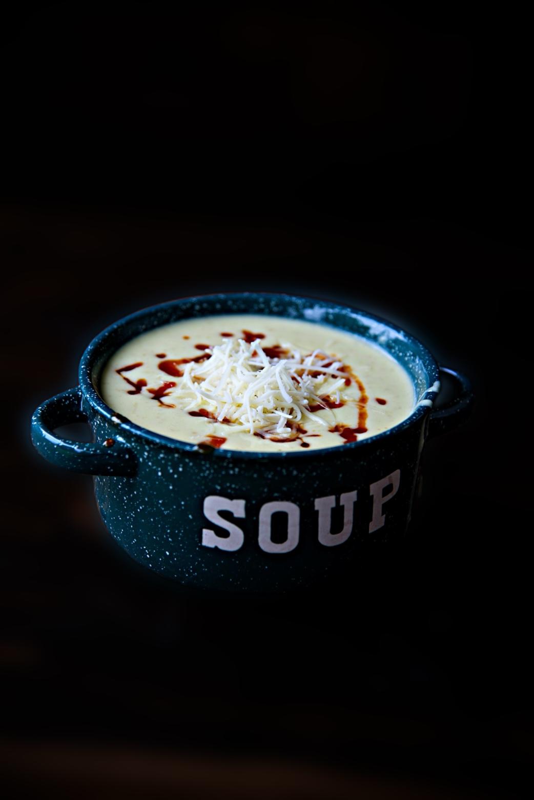 Side view of a full bowl of soup with tomato jam and extra cheese on top.