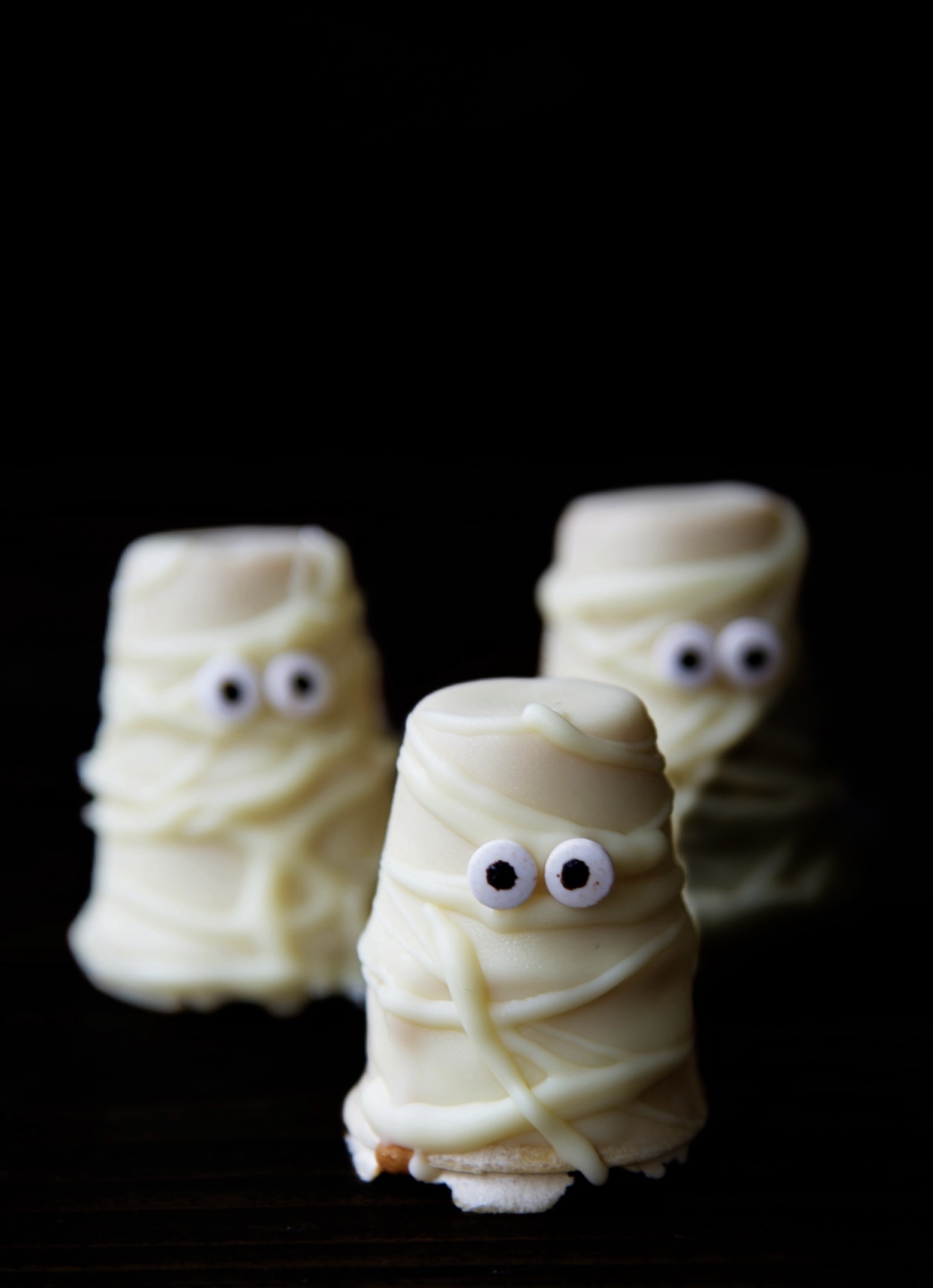 Front view of three Maple Mummy Cupcake Cones with a dark background. 