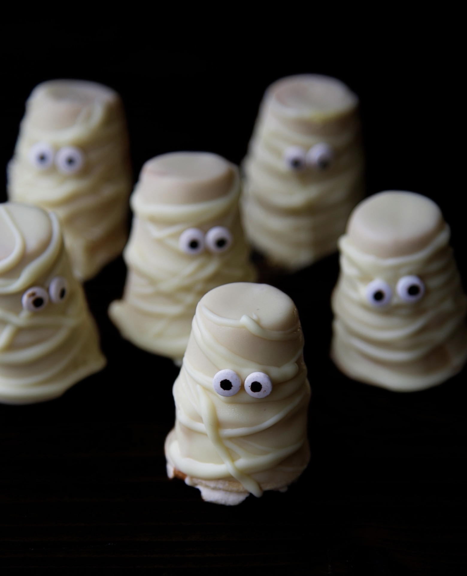 Cluster of mummy cupcakes with a dark background.