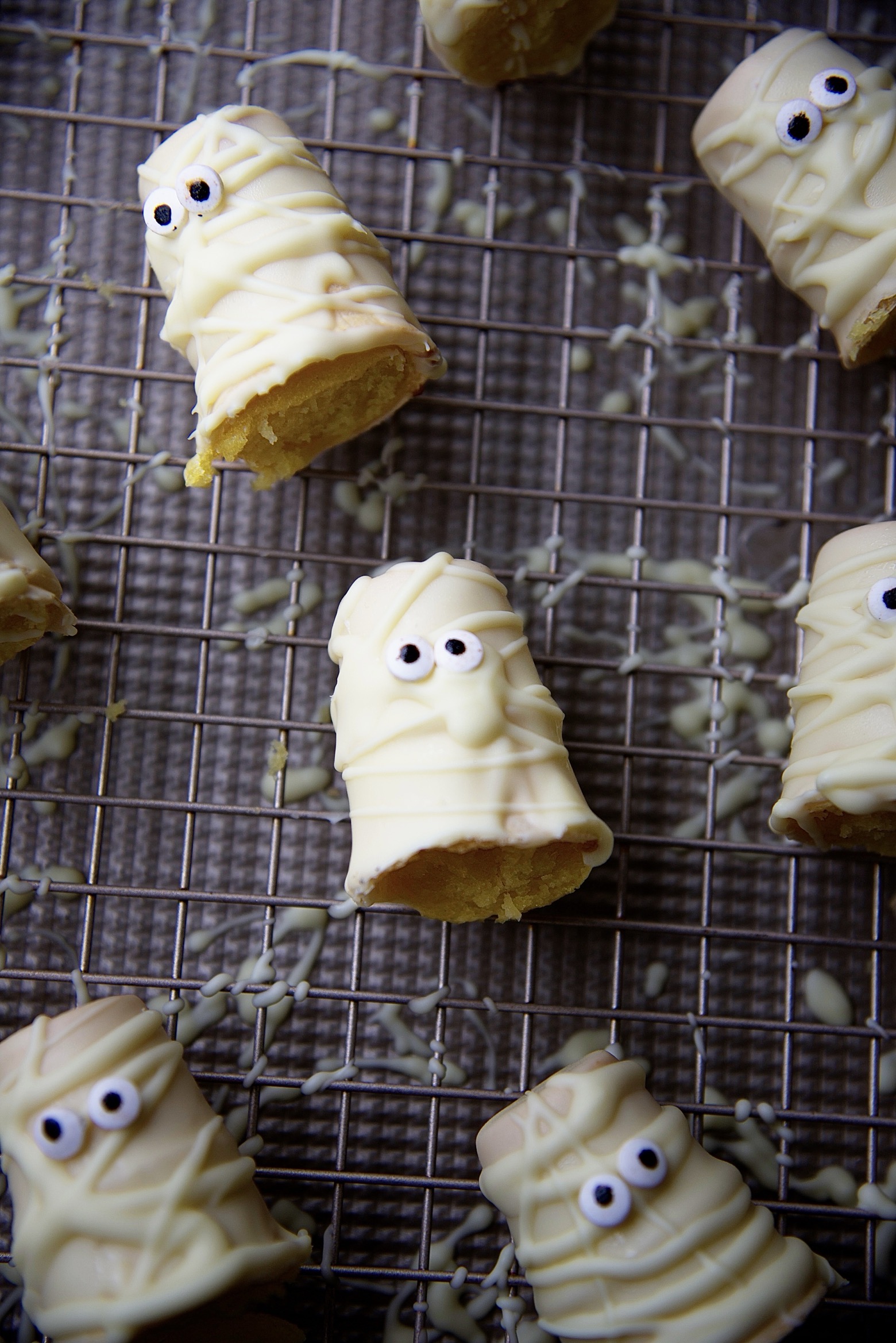 Overhead shot of the cupcake cones on a wire rack where you can see the splattered white chocolate below.