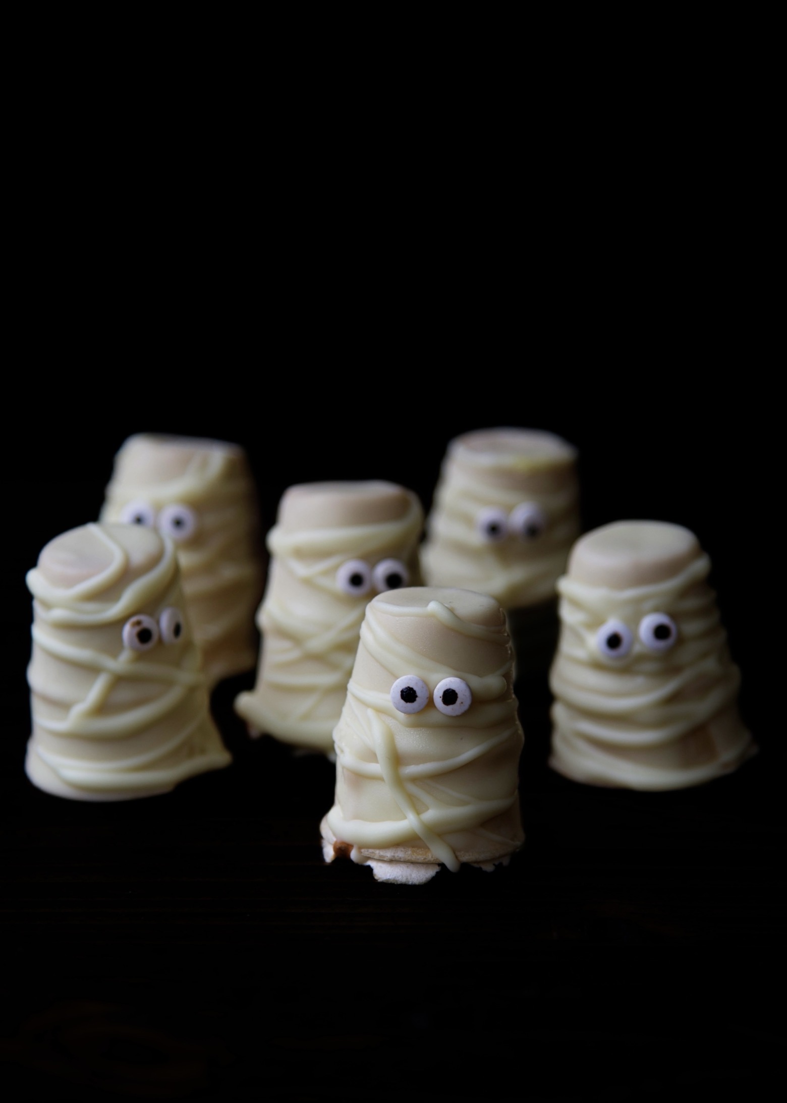Front view of six Maple Mummy Cupcake Cones with a dark background.