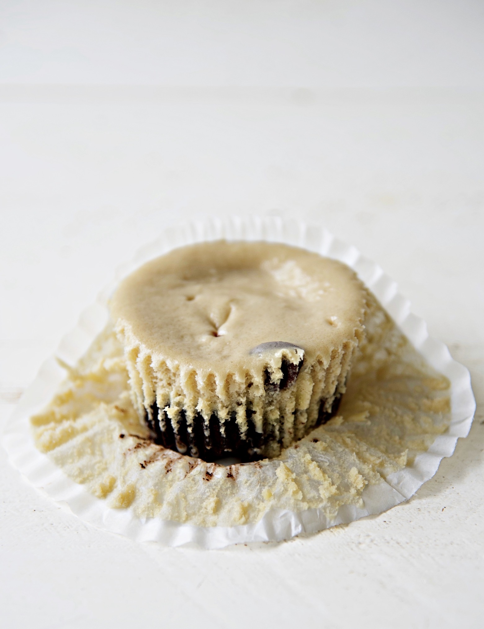 Coffee and Donuts Cheesecake Bite with the cupcake liner pulled back exposing half of the cheesecake bite.