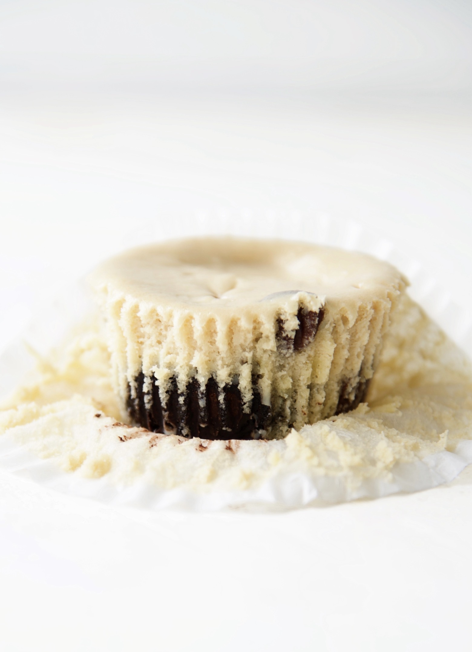 Side view of Coffee and Donuts Cheesecake Bite with the cupcake liner pulled back exposing half of the cheesecake bite.