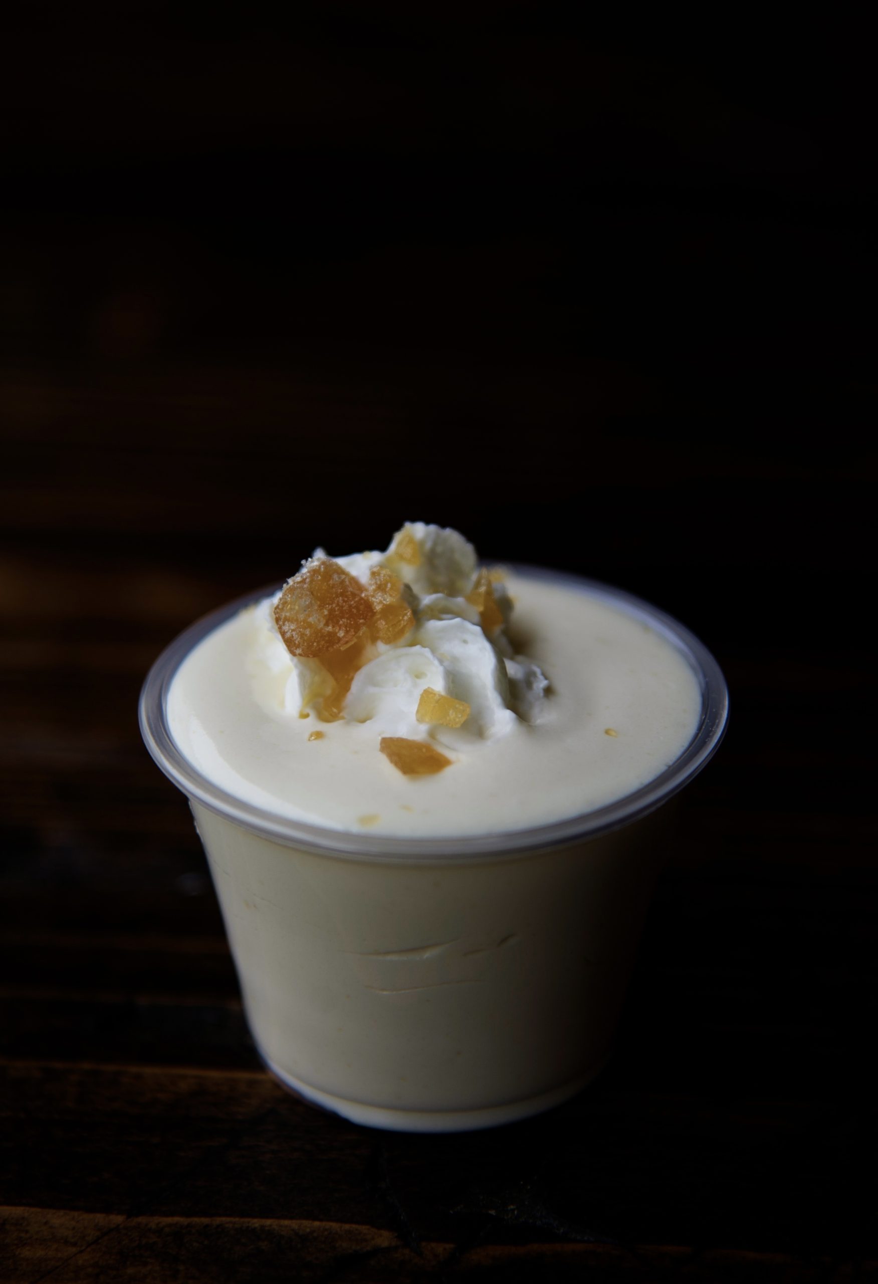 Shot of a single pudding shot with whipped cream and crushed butter rum candies on top. 