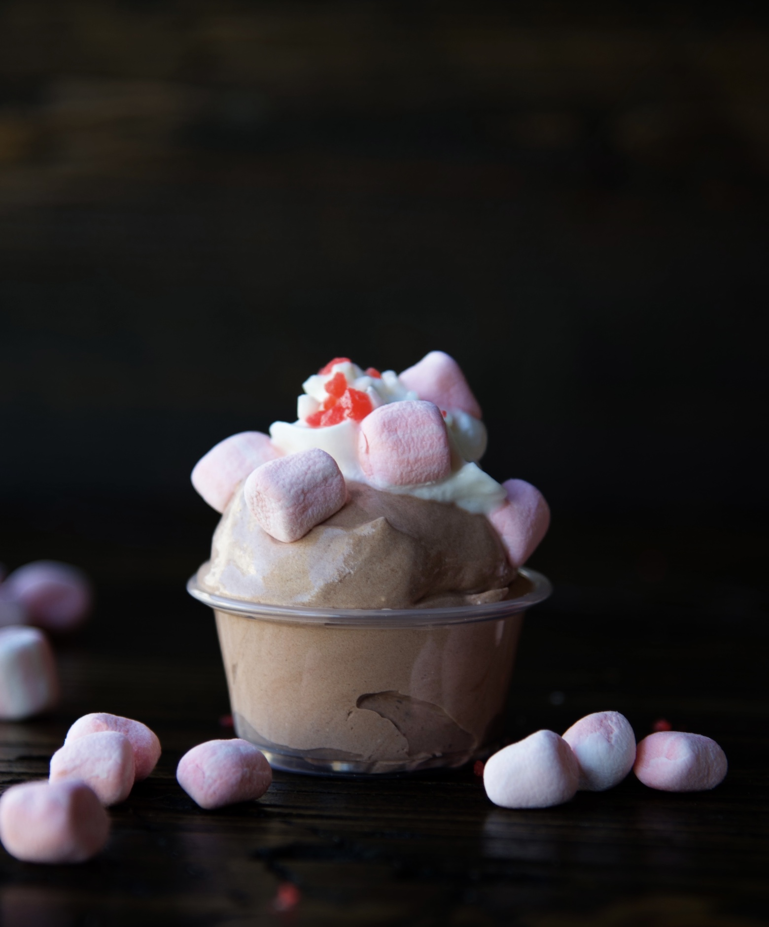 Side view of a single pudding shots with peppermint marshmallows scattered around. 