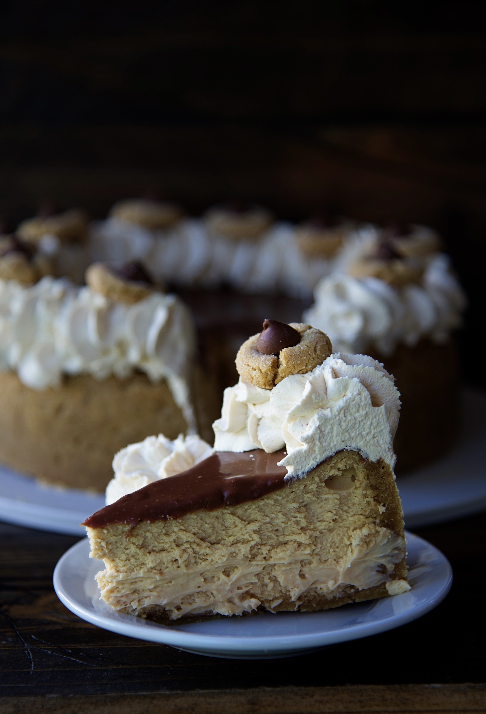 Slice of cheesecake on a small white plate turned to the side with the remaining cheesecake in the background. 