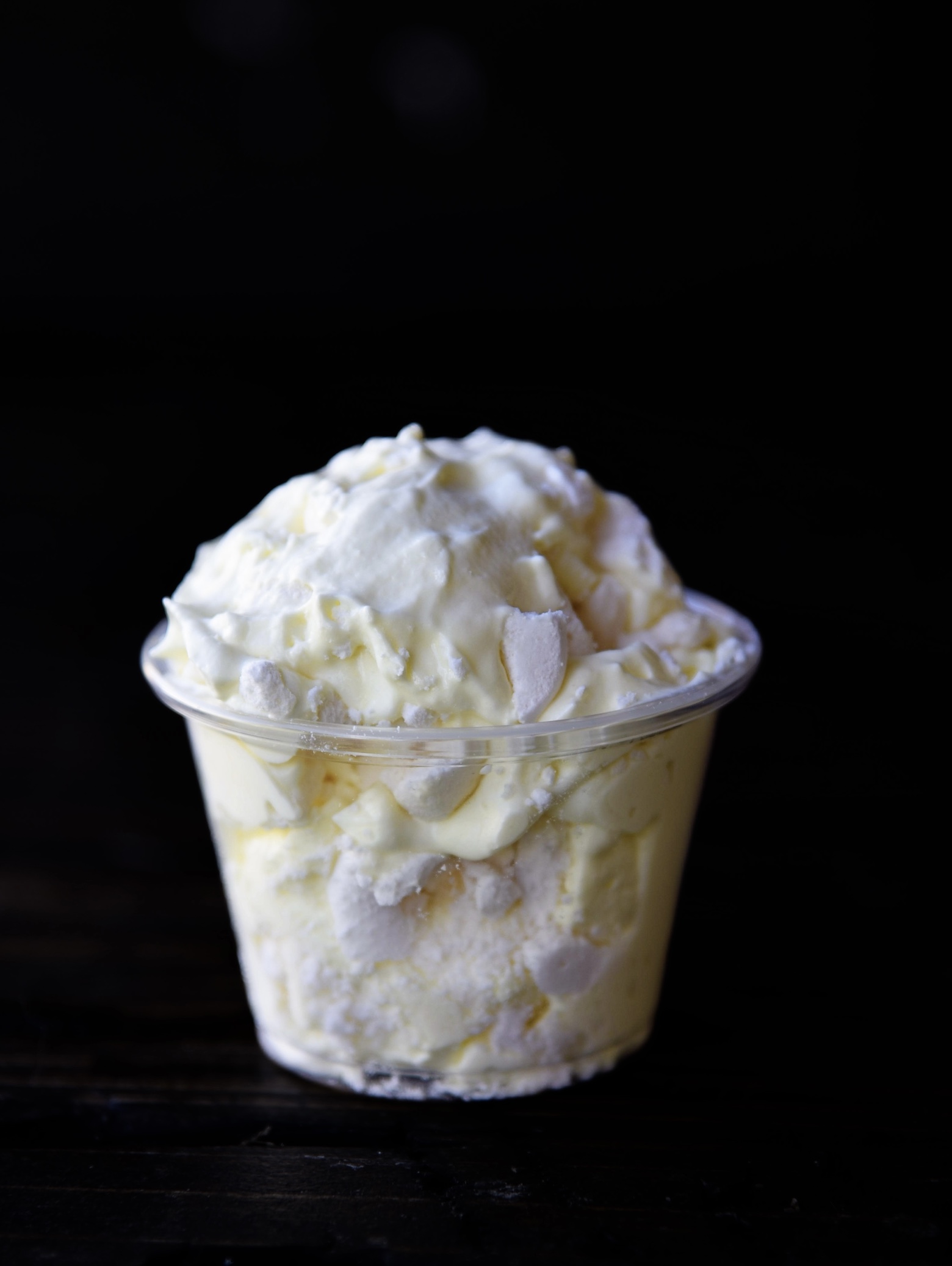 Side view of a single pudding shot with visible meringue pieces. 