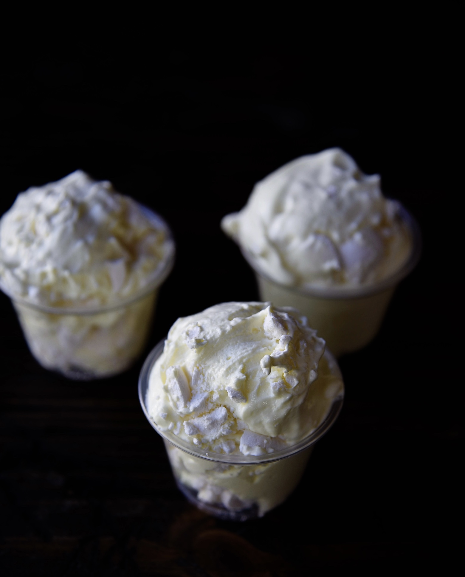 Three quarter view of three pudding shots with with pieces of meringue showing.  