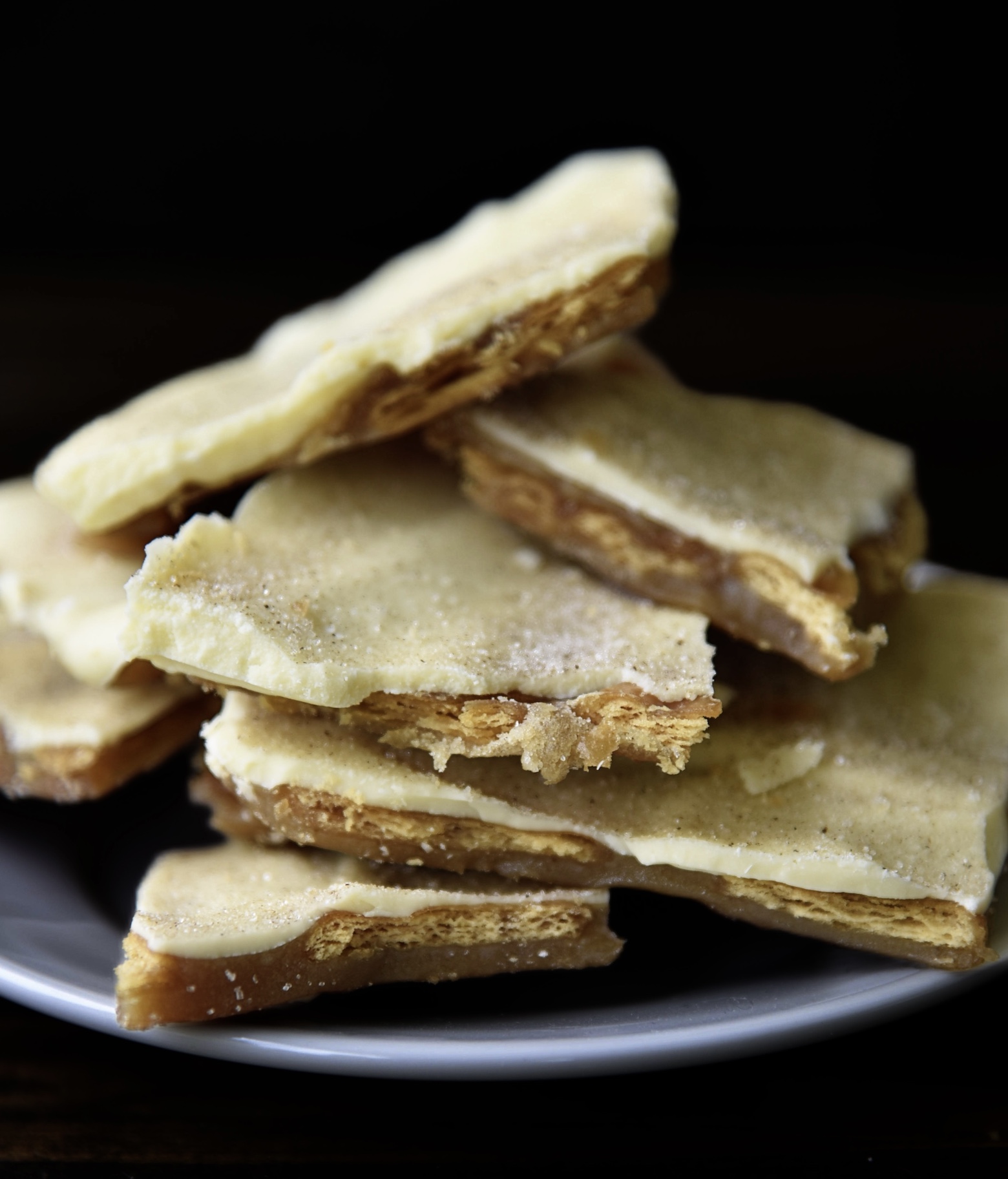 Stack of cinnamon churro cracker toffee on a small white plate.