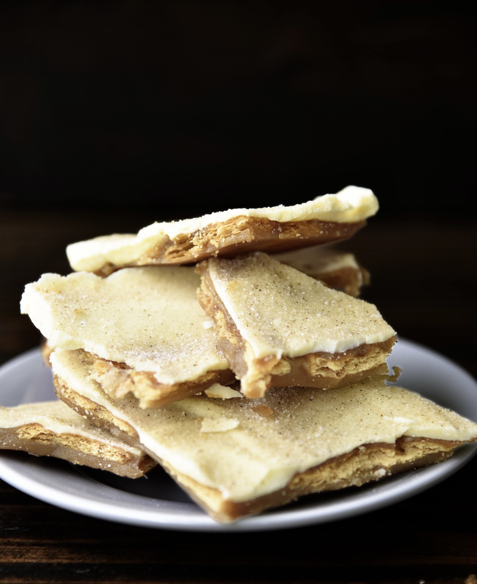 Stack of cinnamon churro cracker toffee on a small white plate.