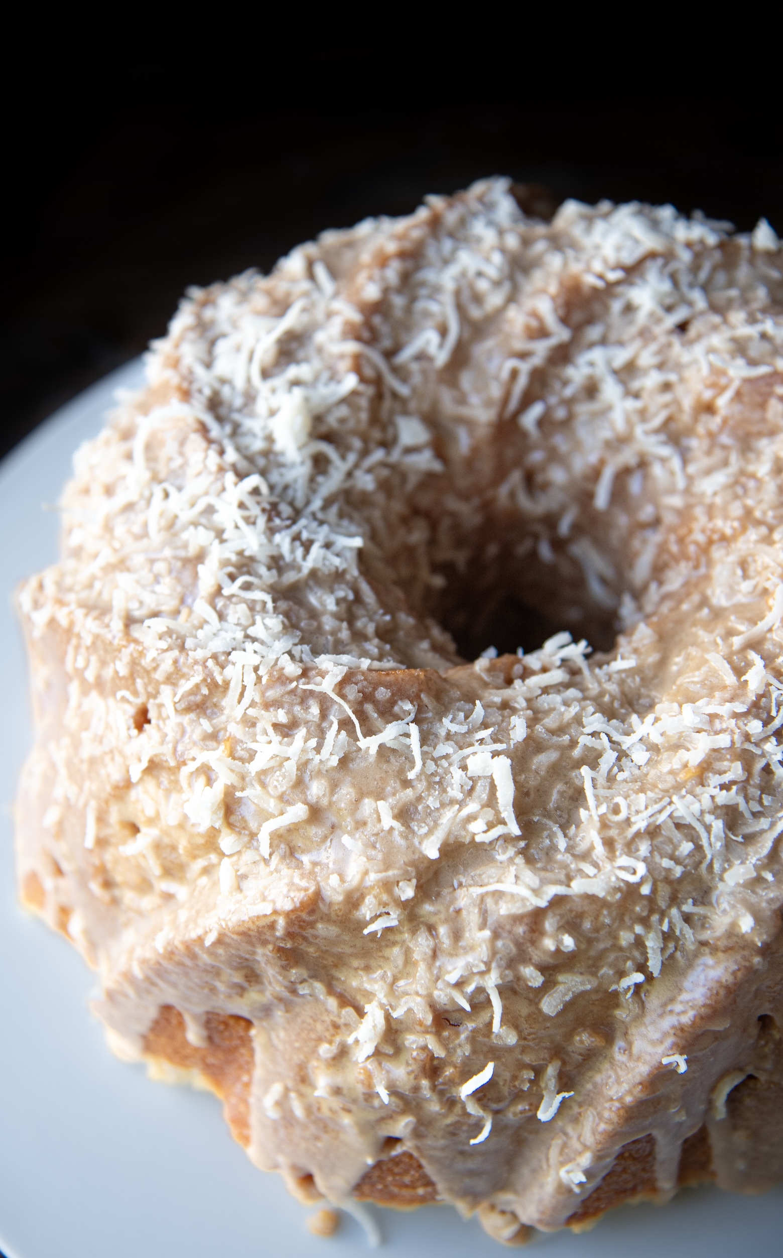 Close up of a pineapple coconut Bundt cake covered in creamy coconut frosting and topped with shredded coconut.